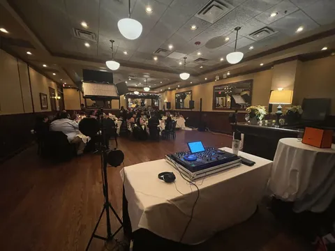 Dinner event room from behind the DJ setup with lighting and guests seated