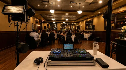Formal indoor event room with DJ setup and guests
