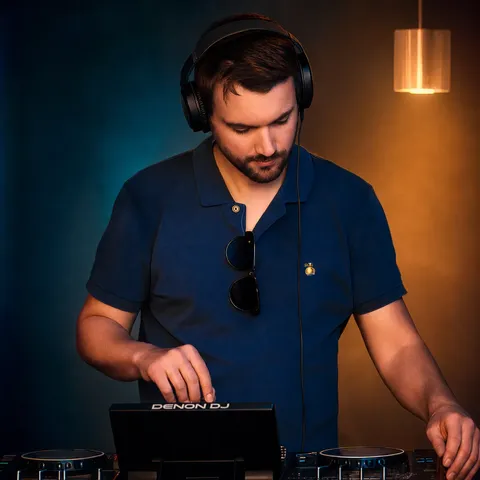 DJ Juan mixing with headphones in warm editorial event lighting
