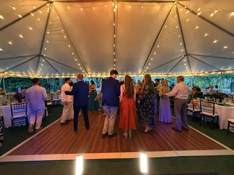 Guests dancing beneath warm string lights at a tented reception